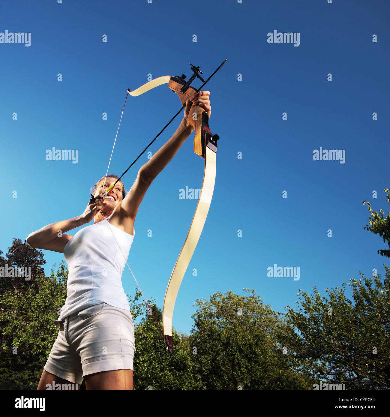 Attraktive Frau, die einen Bogen und mit dem Ziel in den Himmel Stockfoto