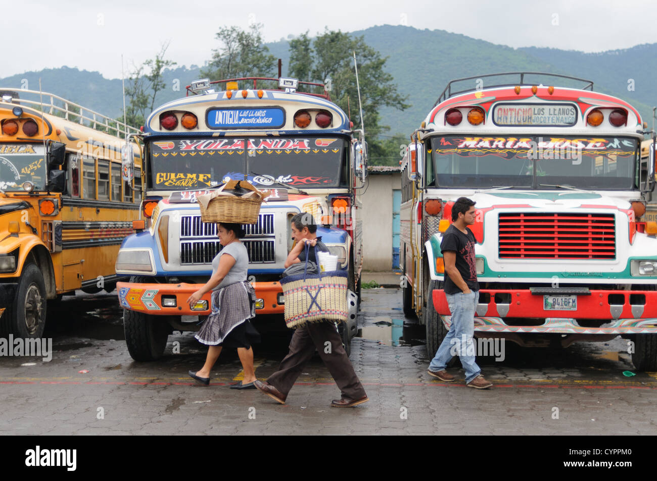 ANTIGUA, Guatemala - Passagiere vor der geparkten Huhn Busse hinter dem Mercado Municipal (Stadt) in Antigua, Guatemala. Aus diesem umfangreichen Central Bus tauschen Sie die Routen strahlenförmig über Guatemala. Oft bunt bemalt, die Hühner Busse nachgerüstet Amerikanischen Schulbusse und ein billiges Verkehrsmittel im ganzen Land. Stockfoto