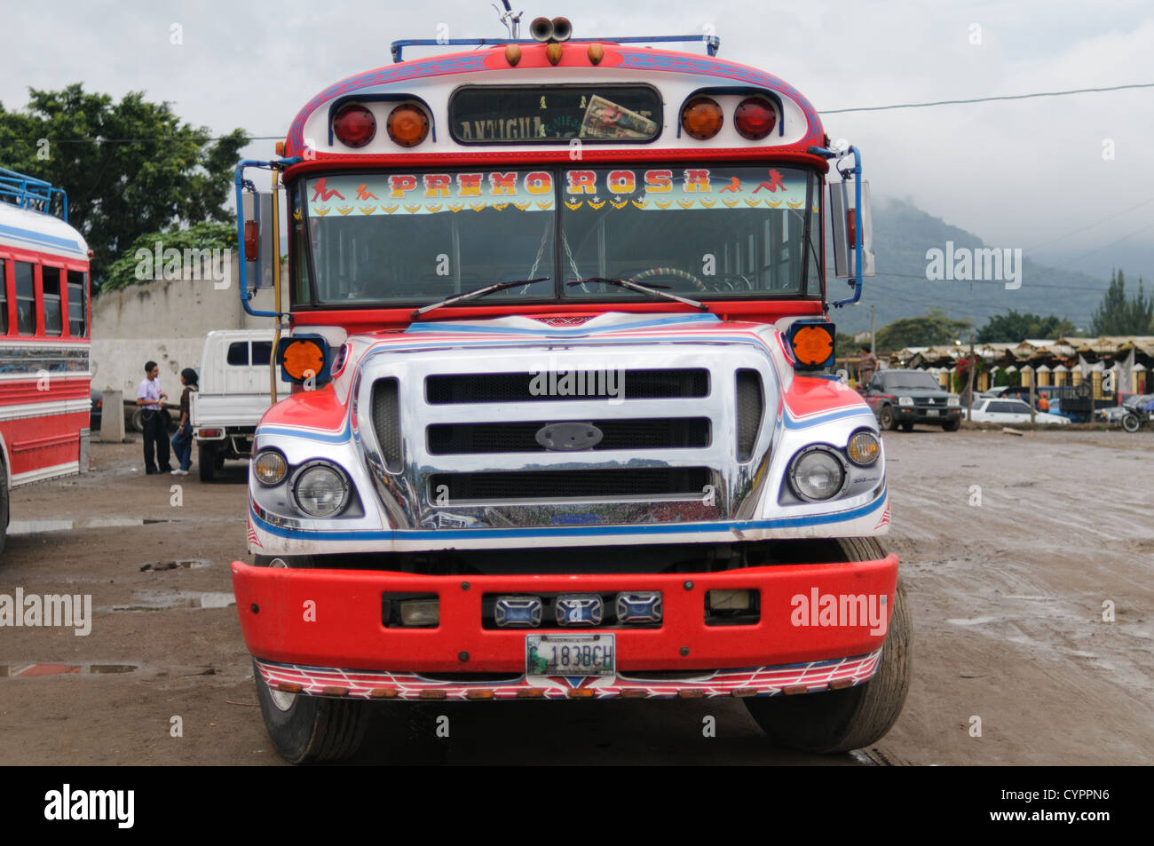 Vorne ein Huhn Bus hinter dem Mercado Municipal (Stadtmarkt) in Antigua, Guatemala. Aus diesem umfangreichen zentralen Busbahnhof strahlenförmig der Routen in Guatemala. Oft bunt bemalt, die Huhn-Busse sind nachgerüsteten amerikanische Schulbusse und bieten ein günstiges Transportmittel im ganzen Land. Stockfoto