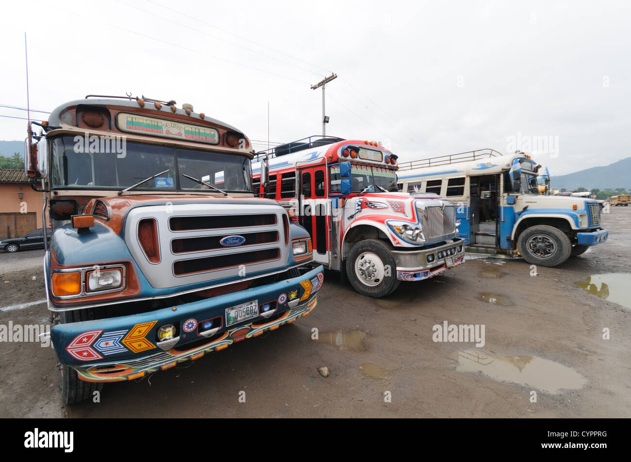 Bunt bemalten Huhn Busse hinter dem Mercado Municipal (Stadtmarkt) in Antigua, Guatemala. Aus diesem umfangreichen zentralen Busbahnhof strahlenförmig der Routen in Guatemala. Oft bunt bemalt, die Huhn-Busse sind nachgerüsteten amerikanische Schulbusse und bieten ein günstiges Transportmittel im ganzen Land. Stockfoto