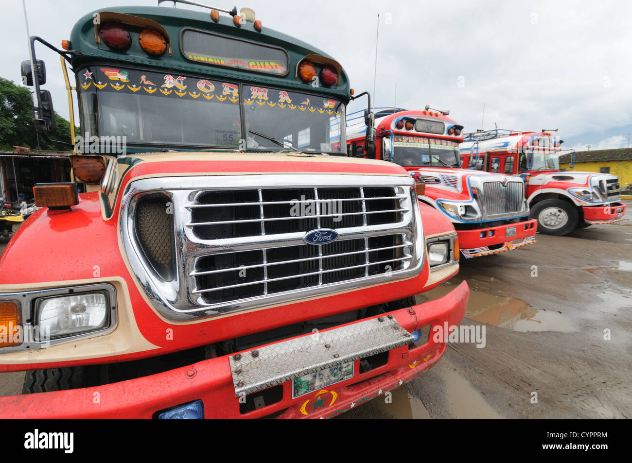 Fronten von Huhn Busse hinter dem Mercado Municipal (Stadtmarkt) in Antigua, Guatemala. Aus diesem umfangreichen zentralen Busbahnhof strahlenförmig der Routen in Guatemala. Oft bunt bemalt, die Huhn-Busse sind nachgerüsteten amerikanische Schulbusse und bieten ein günstiges Transportmittel im ganzen Land. Stockfoto