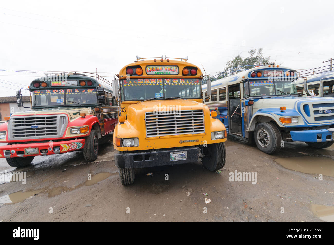 Drei Huhn Busse hinter dem Mercado Municipal (Stadtmarkt) in Antigua, Guatemala. Aus diesem umfangreichen zentralen Busbahnhof strahlenförmig der Routen in Guatemala. Oft bunt bemalt, die Huhn-Busse sind nachgerüsteten amerikanische Schulbusse und bieten ein günstiges Transportmittel im ganzen Land. Stockfoto