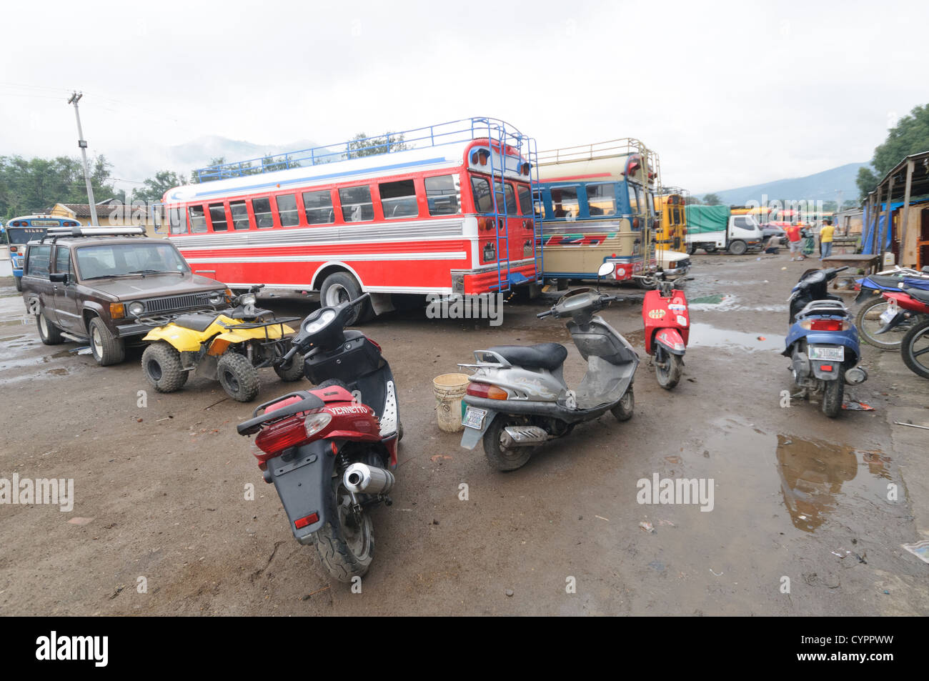 Huhn Busse und Motorroller hinter dem Mercado Municipal (Stadtmarkt) in Antigua, Guatemala. Aus diesem umfangreichen zentralen Busbahnhof strahlenförmig der Routen in Guatemala. Oft bunt bemalt, die Huhn-Busse sind nachgerüsteten amerikanische Schulbusse und bieten ein günstiges Transportmittel im ganzen Land. Stockfoto