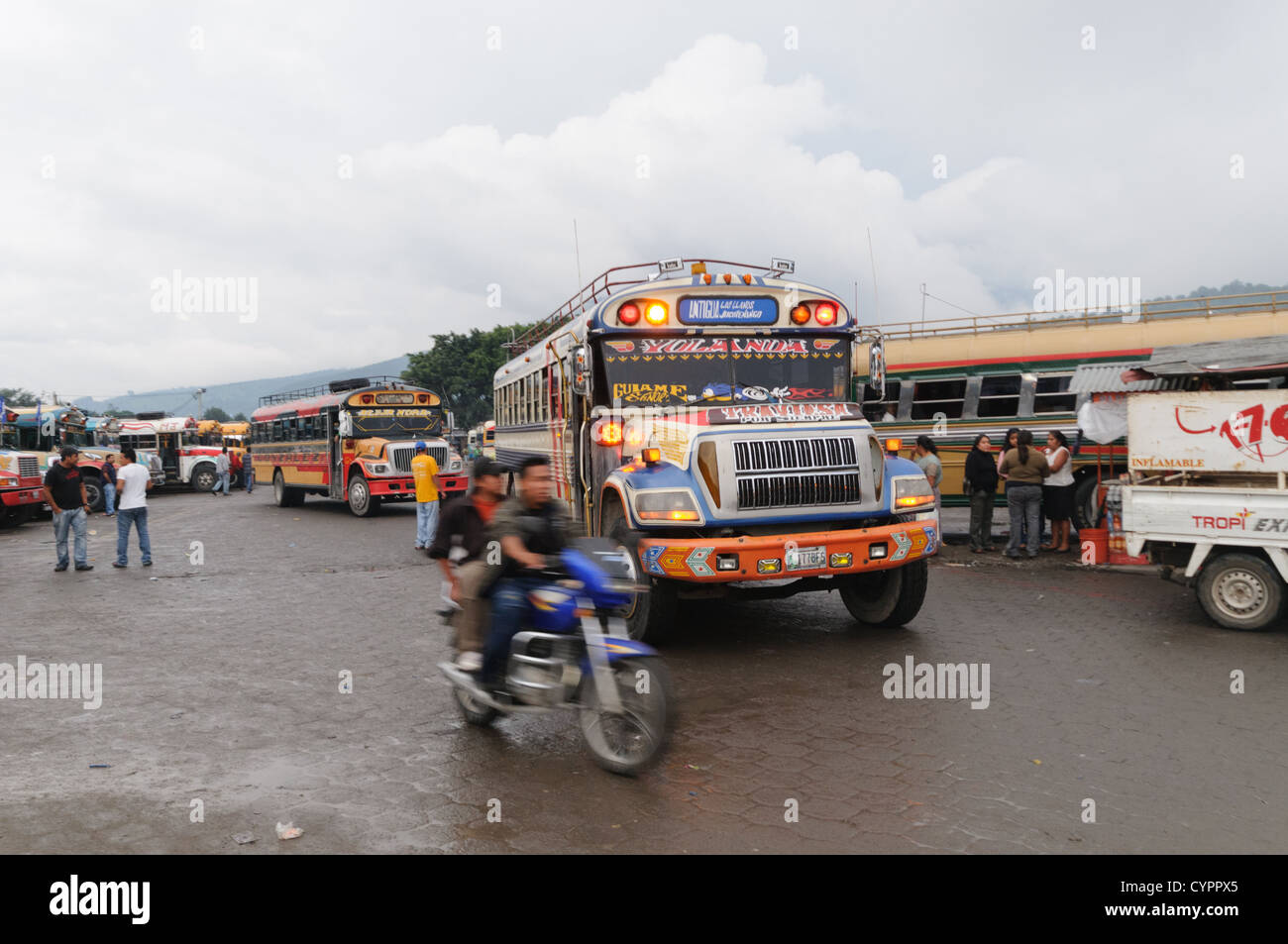 Huhn-Busse und ein Motorrad hinter dem Mercado Municipal (Stadtmarkt) in Antigua, Guatemala. Aus diesem umfangreichen zentralen Busbahnhof strahlenförmig der Routen in Guatemala. Oft bunt bemalt, die Huhn-Busse sind nachgerüsteten amerikanische Schulbusse und bieten ein günstiges Transportmittel im ganzen Land. Stockfoto