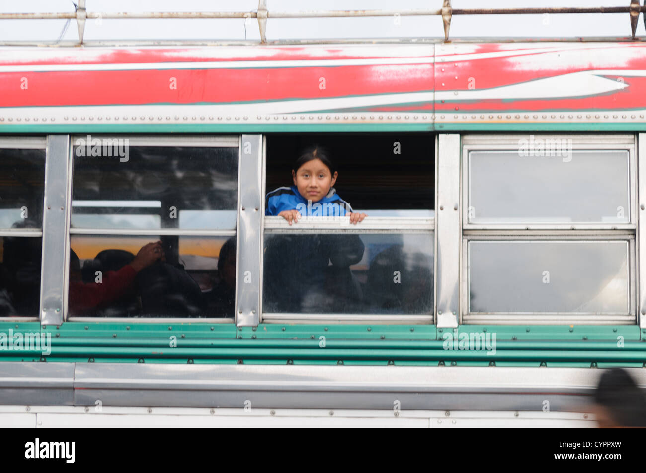Ein junges Mädchen lehnt sich aus dem Fenster auf einem Huhn Bus hinter dem Mercado Municipal (Stadtmarkt) in Antigua, Guatemala. Aus diesem umfangreichen zentralen Busbahnhof strahlenförmig der Routen in Guatemala. Oft bunt bemalt, die Huhn-Busse sind nachgerüsteten amerikanische Schulbusse und bieten ein günstiges Transportmittel im ganzen Land. Stockfoto