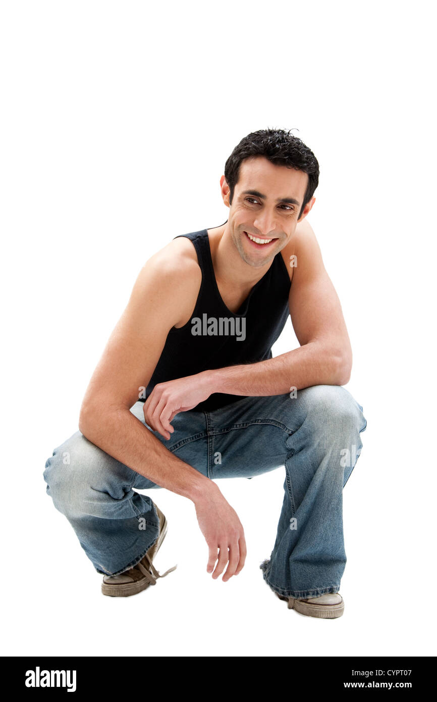 Gut aussehend lächelnd kaukasischen Mann in schwarzen Tank-Top und Jeans hocken, isoliert Stockfoto