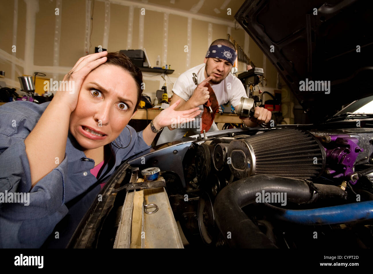 Frustrierte Frau stützte sich auf Auto mit inkompetenten männlichen Mechaniker im Hintergrund Stockfoto