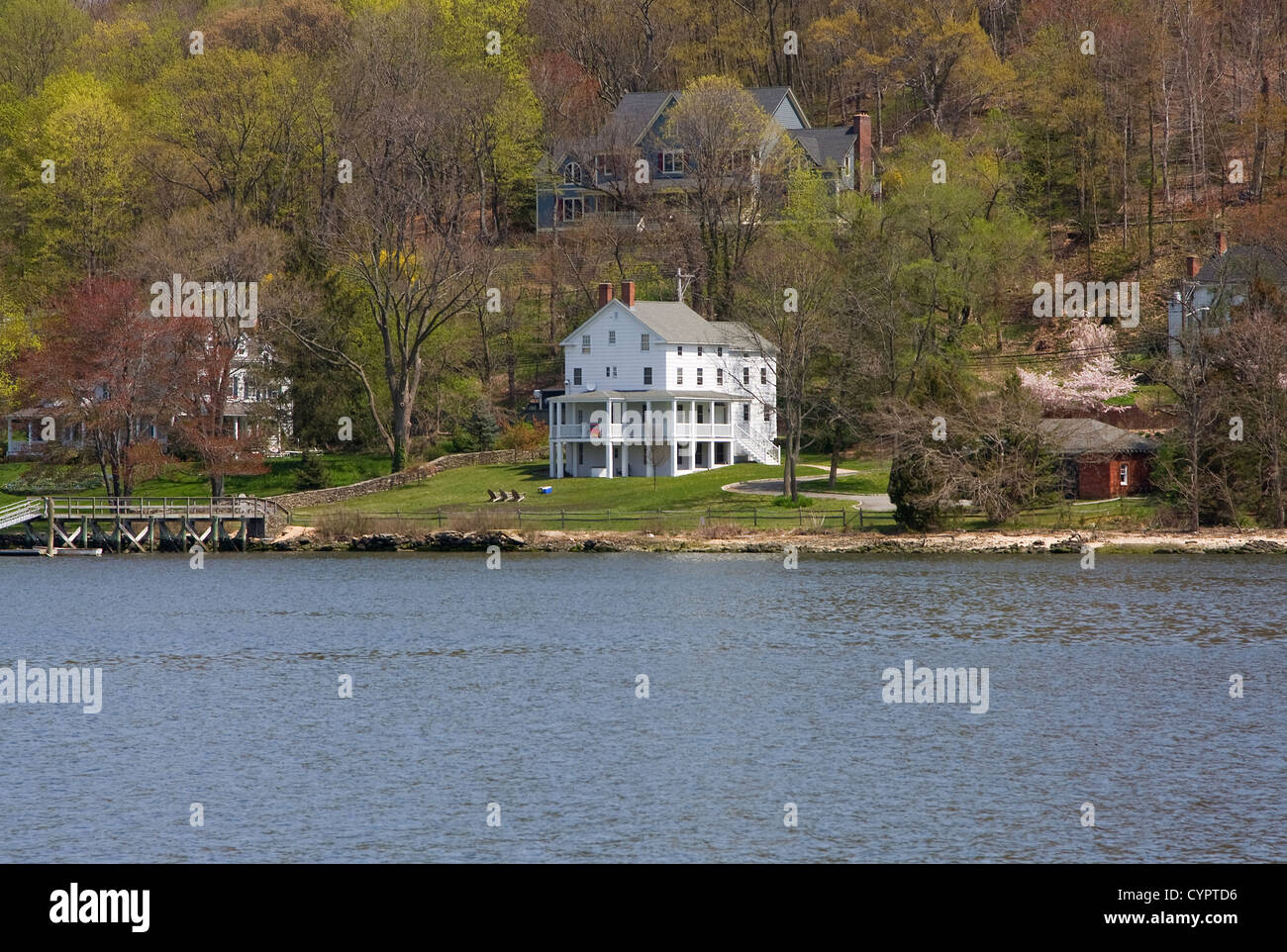 Eine weit entfernte weiße viktorianisches Herrenhaus auf dem Wasser und im Wald an einem Frühlingstag. Stockfoto