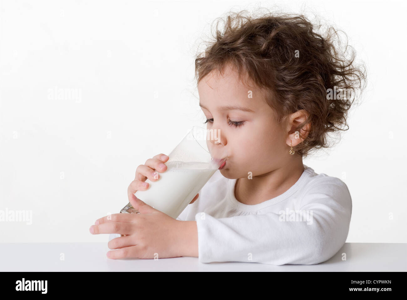 Kaukasische Mädchen, ca. 5-6 Jahre alt, lockiges Haar, trinken ein Glas Milch, isoliert auf weißem Hintergrund Stockfoto