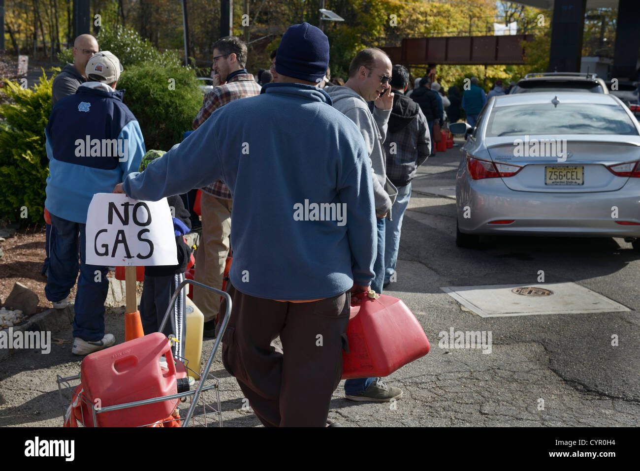 Linie an Tankstelle nach Hurrikan Sandy, northern NJ.  Menschen mit Dosen, die darauf warten, Gas für Autos und Generatoren zu erhalten. Stockfoto