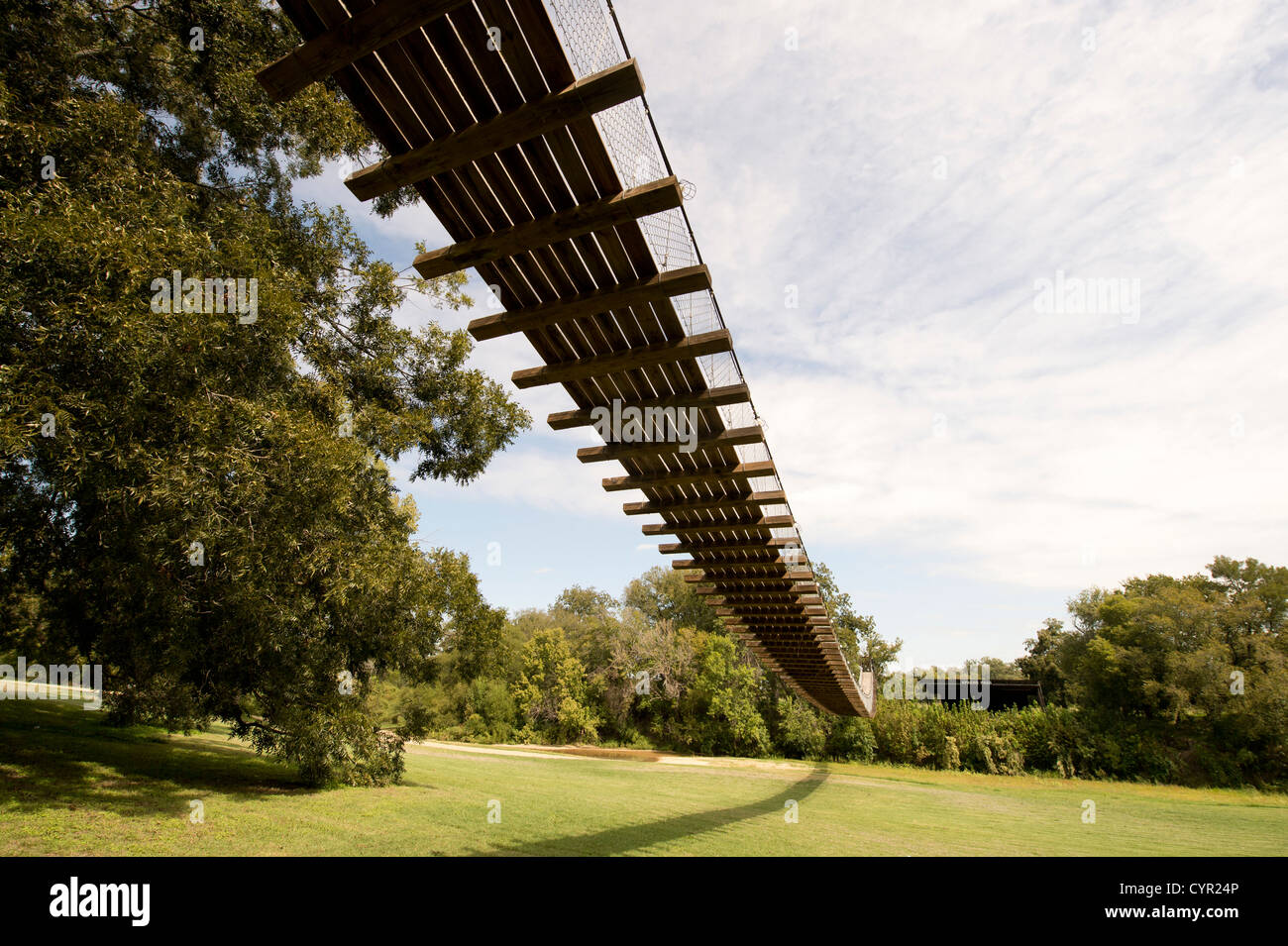 Eine schwingende Fußgängerbrücke hängt über dem San Gabriel River grasbewachsenen Bank in Zentral-Texas. Stockfoto