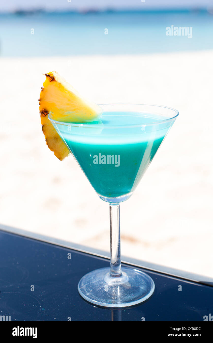 Blue Curacao cocktail mit Scheibe Ananas am weißen Strand Stockfoto