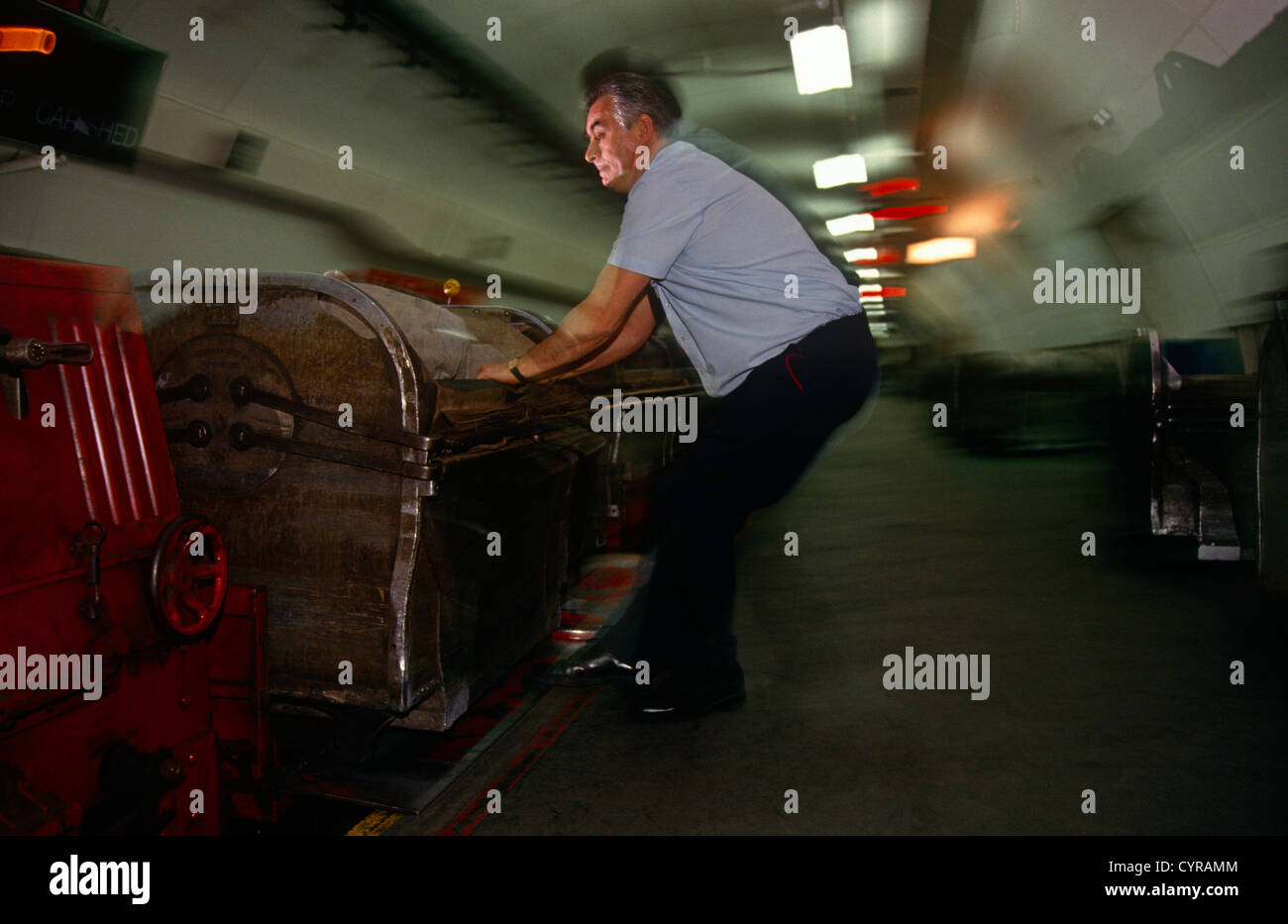 Ein Post-Office-Mitarbeiter schleppt einen Wagen voller Post auf dem Bahnsteig auf dem Mail-Schienensystem. Stockfoto