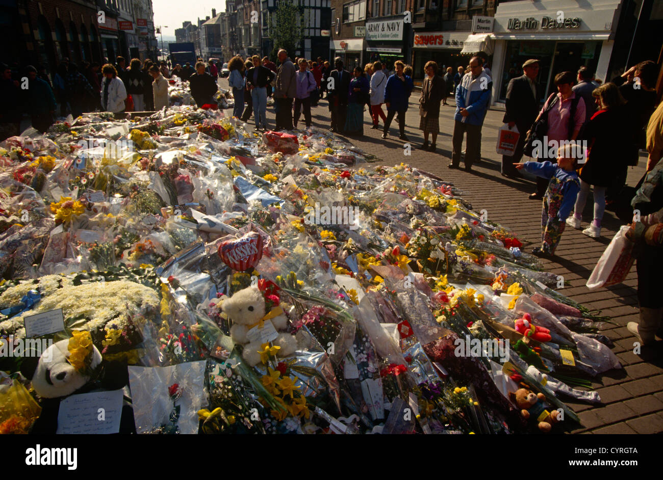 Einheimische Zahlen Beziehung zu einem wachsenden Hügel aus einen floralen Denkmal in Erinnerung an zwei Menschen durch eine Bombe der IRA in Warrington Bombe getötet. Stockfoto