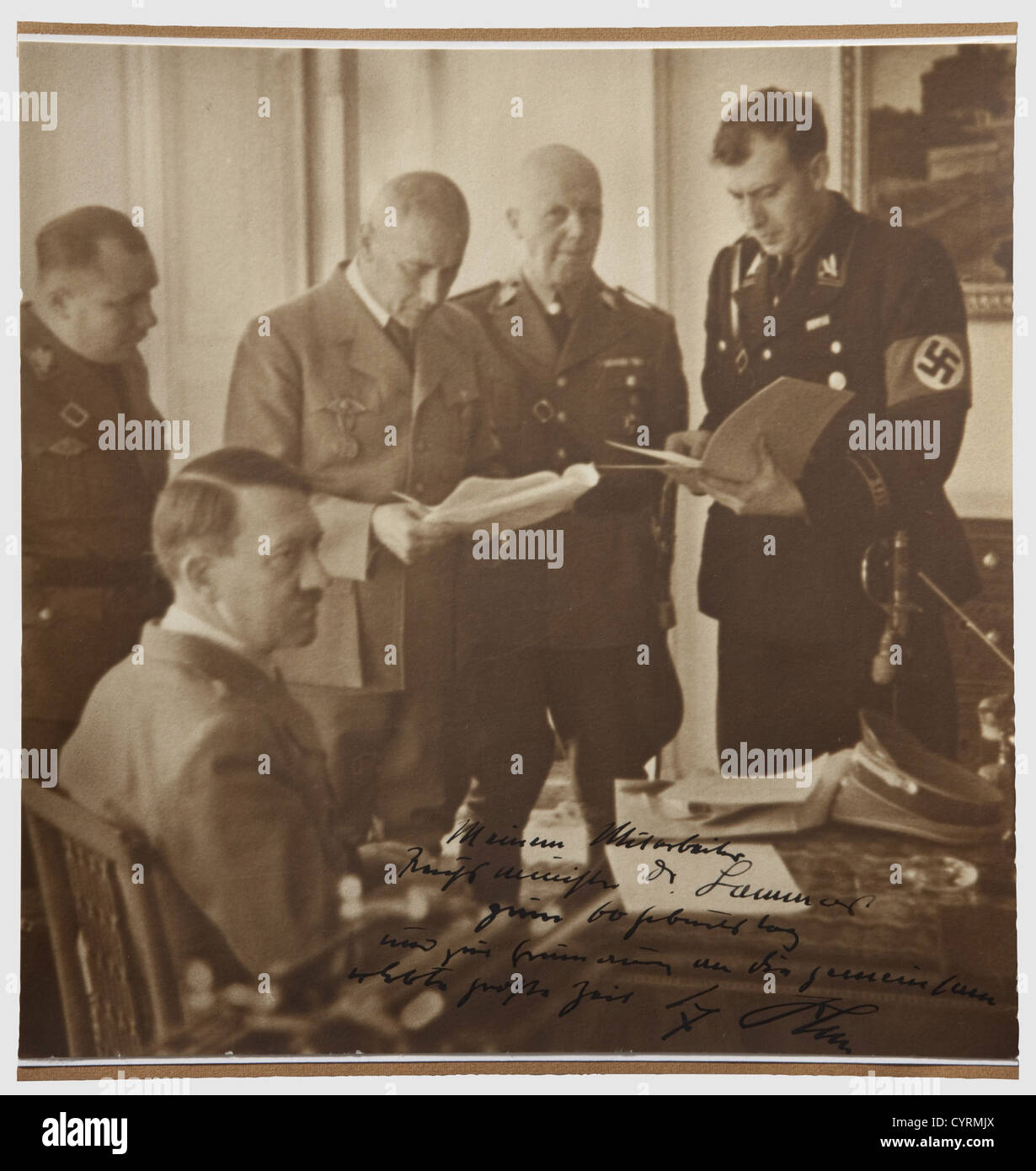 Adolf Hitler,ein Foto, das Hans-Heinrich Lammers anlässlich seines 60. Geburtstages gewidmet ist.Großbild (24 x 23.7 cm beschnitten?),Hitler an seinem Schreibtisch sitzend,vor ihm Reichsminister Lammers und Frick sowie Reichsleiter Martin Bormann und SS-Gruppenführer Wilhelm Stuckart,der untere Rand mit handgeschriebener Tuschendeihe 'an meinen Assistenten, Reichsminister Dr.Lammers,zu seinem 60. Geburtstag und in Erinnerung an ereignisreiche Zeiten gingen wir gemeinsam durch - Adolf Hitler.' Gut lesbares Autogramm auf Bild mit fetter Tinte aufgetragen, Zusatz-Rechte-Clearenzen-nicht verfügbar Stockfoto