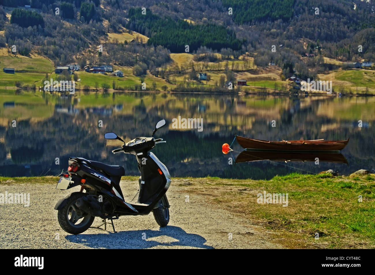 Ein Roller geparkt an einem Strand vor einem hölzernen Ruderboot Stockfoto