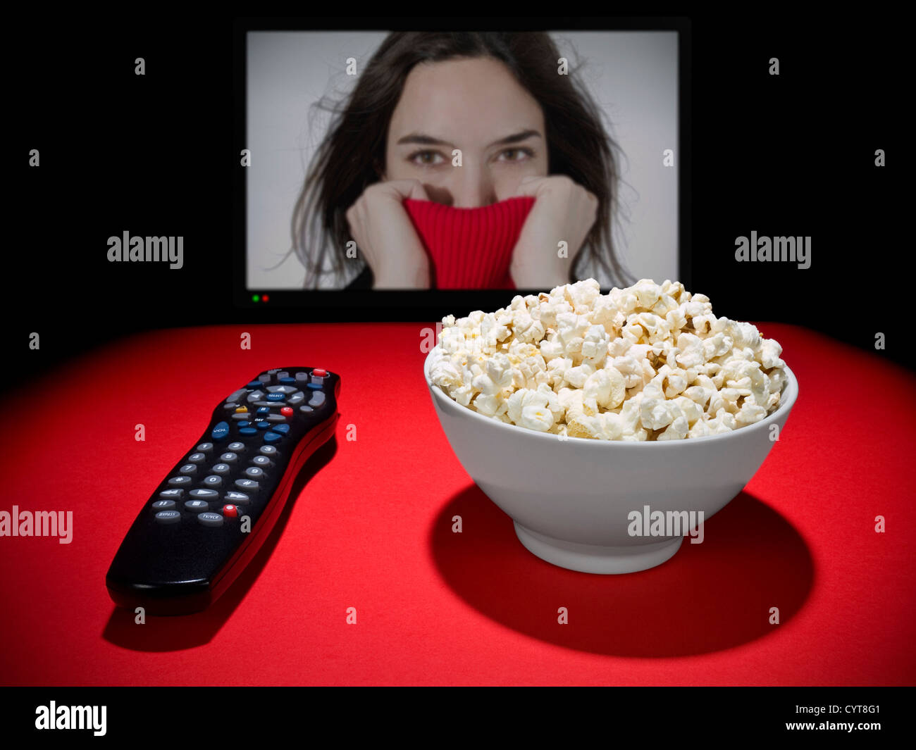 Eine Schüssel Popcorn und eine Fernbedienung. Einem großen TV-Bildschirm als Hintergrund. Stockfoto