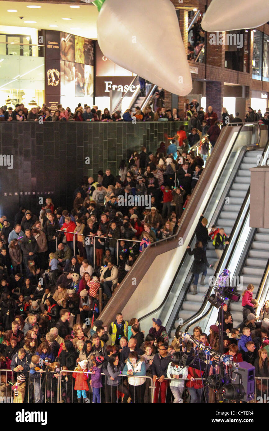 Eine Prozession von Lost Boy Trommler und 150-köpfige Prozession der Jugend Theater Schule Kinder tanzen ihren Weg aus den Galerien zu Cabot Circus. Bristol-basierte Cirque Bijou unterhalten mit Akrobatik, Stelzenläufer und Gaukler Massen vor die Weihnachtsbeleuchtung beleuchtet sind. Stockfoto