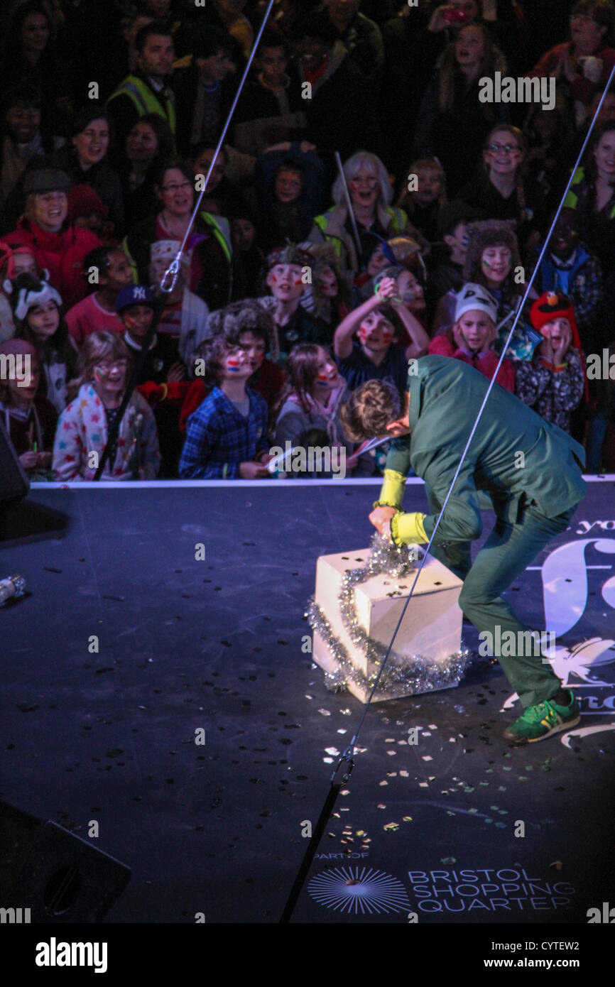 Eine Prozession von Lost Boy Trommler und 150-köpfige Prozession der Jugend Theater Schule Kinder tanzen ihren Weg aus den Galerien zu Cabot Circus. Bristol-basierte Cirque Bijou unterhalten mit Akrobatik, Stelzenläufer und Gaukler Massen vor die Weihnachtsbeleuchtung beleuchtet sind. Stockfoto