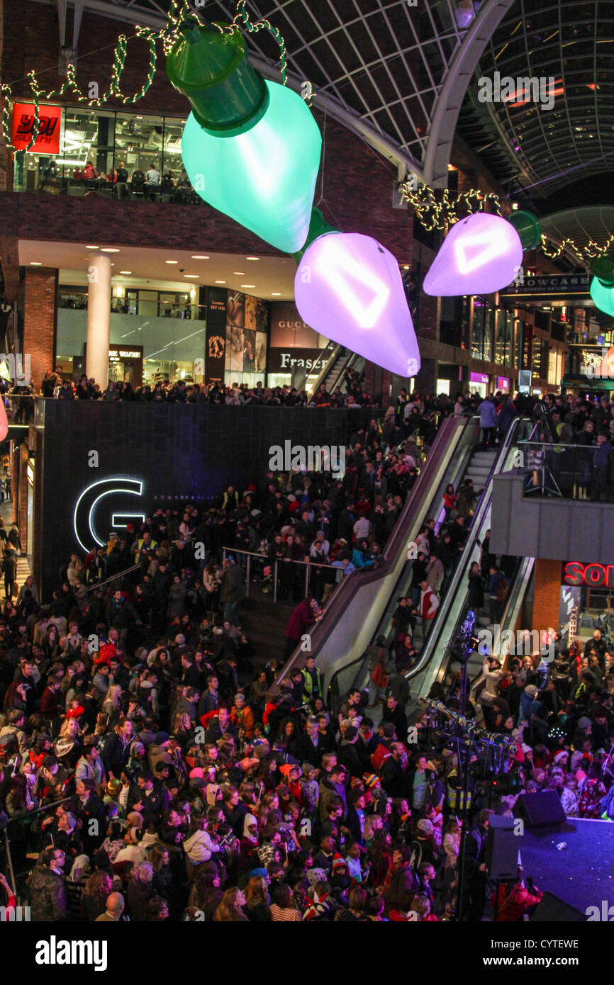 Eine Prozession von Lost Boy Trommler und 150-köpfige Prozession der Jugend Theater Schule Kinder tanzen ihren Weg aus den Galerien zu Cabot Circus. Bristol-basierte Cirque Bijou unterhalten mit Akrobatik, Stelzenläufer und Gaukler Massen vor die Weihnachtsbeleuchtung beleuchtet sind. Stockfoto