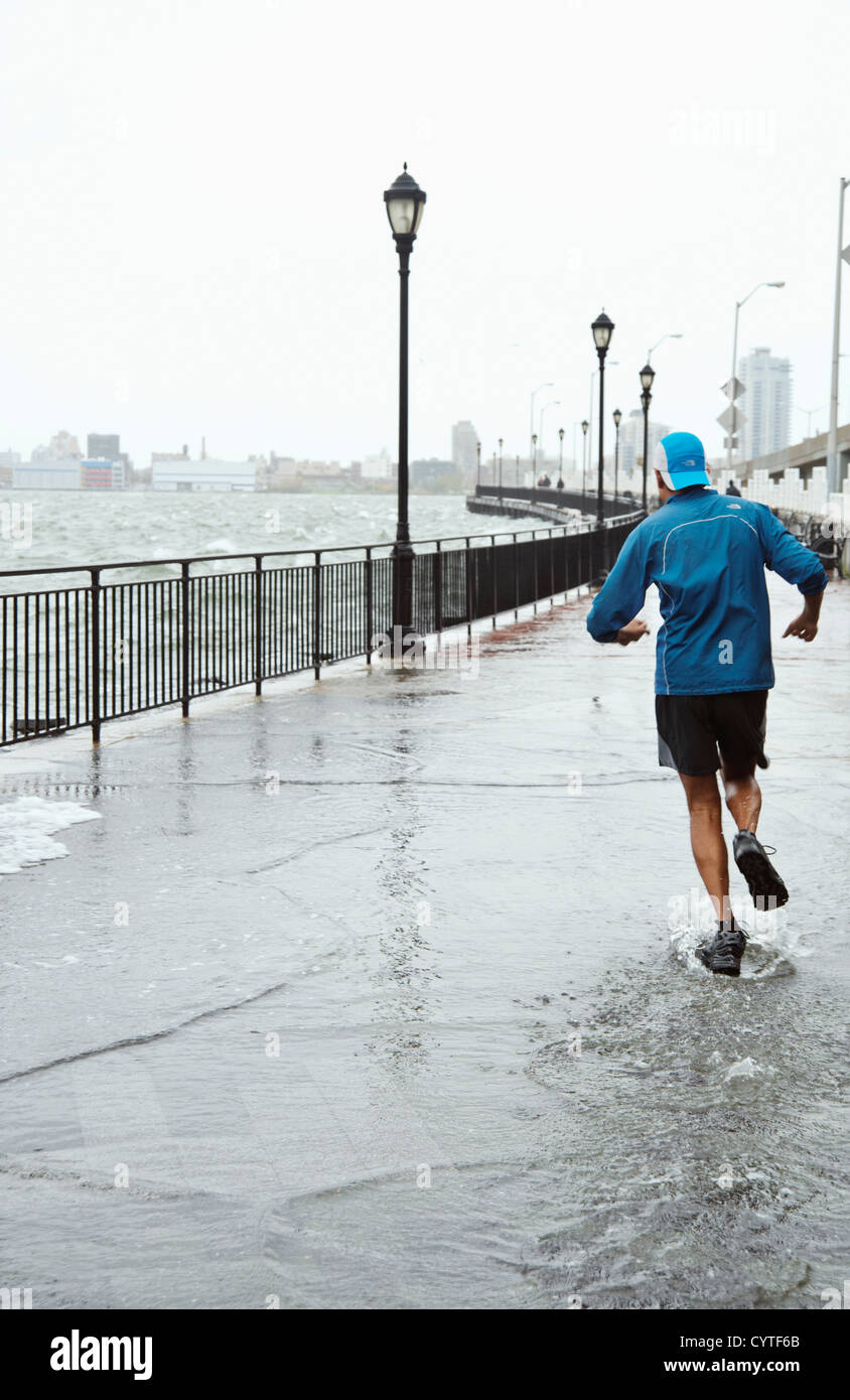 Ein Jogger läuft durch den steigenden Wassern des East River in New York City als Hurrikan Sandy näherte sich der Gegend von New York. Stockfoto