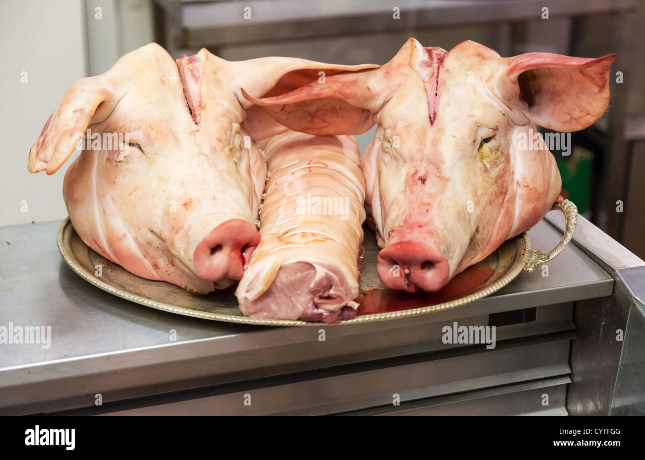Paar Schweine Köpfe auf Tablett in einem Metzger-Shop mit einem starrte auf den Betrachter Stockfoto