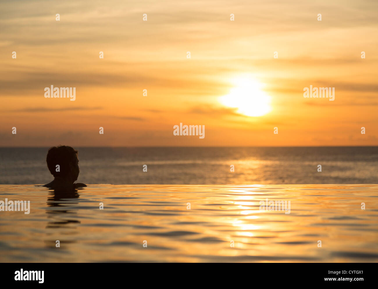 Silhouette des Kopfes am Rande eines schönen Infinity-Pool mit Blick auf den Sunset Ocean Stockfoto