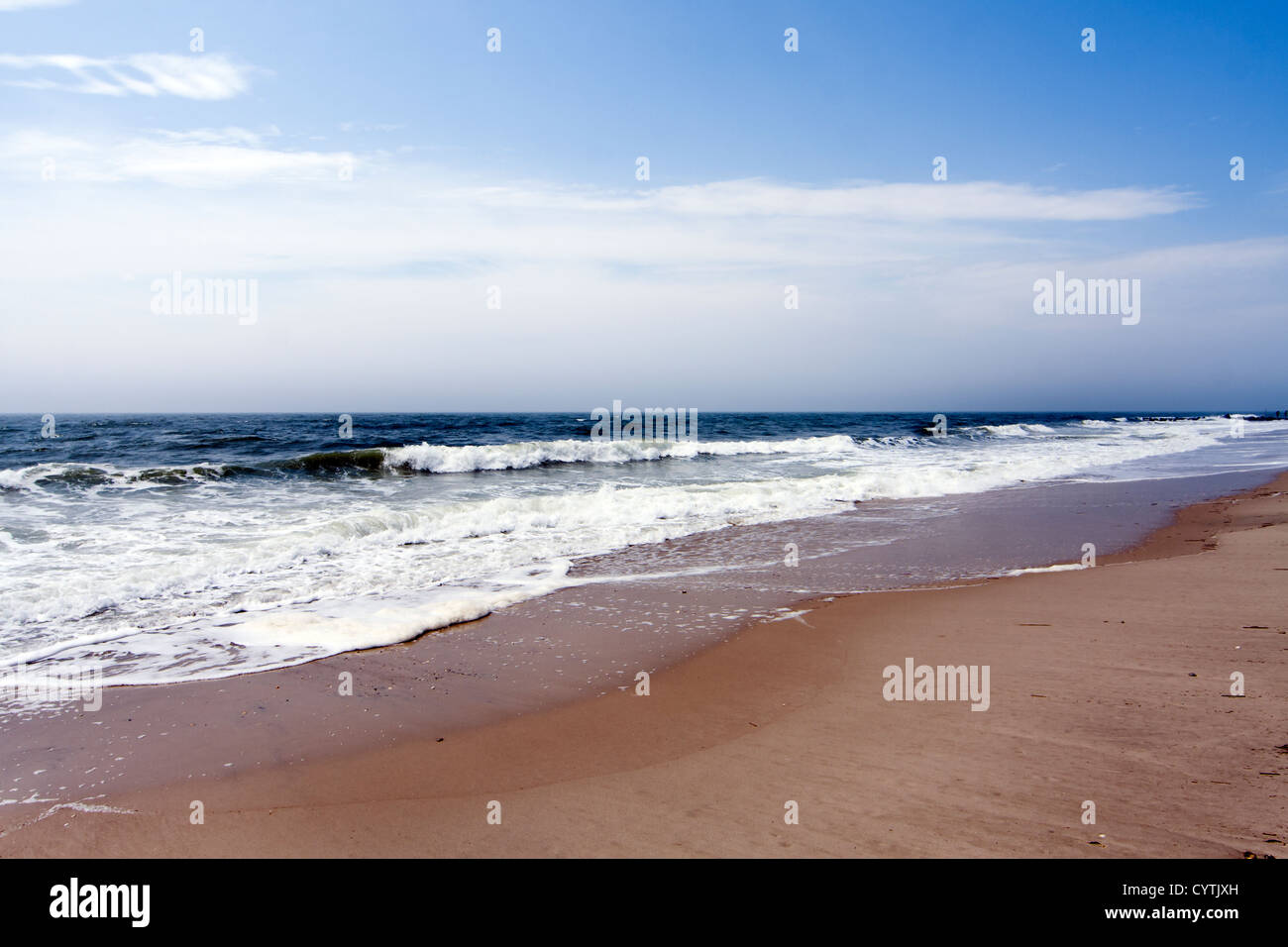 Schöner Strand mit Meer rollenden Wellen unter blauem Himmel mit weißen Wolken, Strömungen. Stockfoto