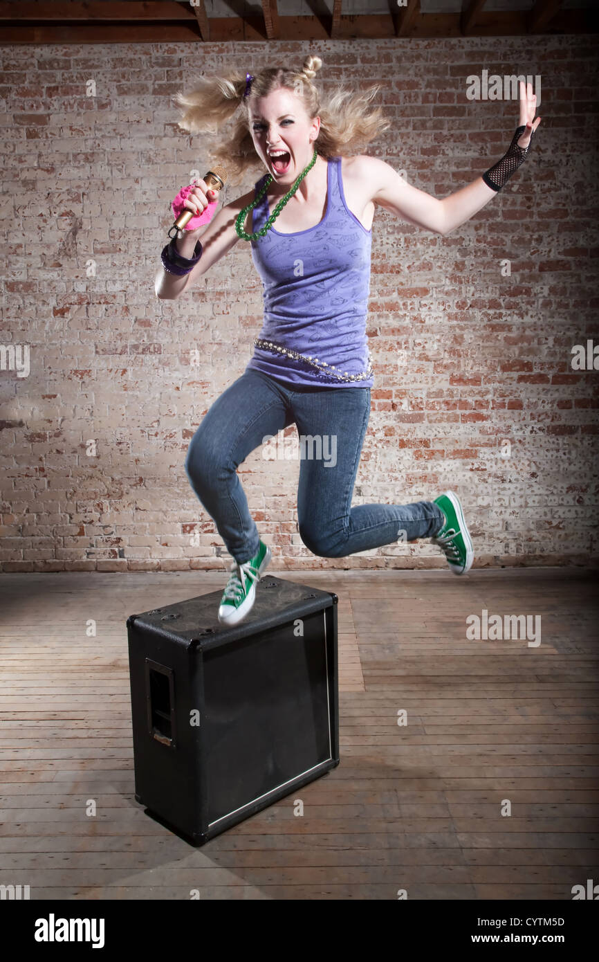 Jungen Punk-Rocker springt von einem Lautsprecher vor einem Backstein-Hintergrund Stockfoto