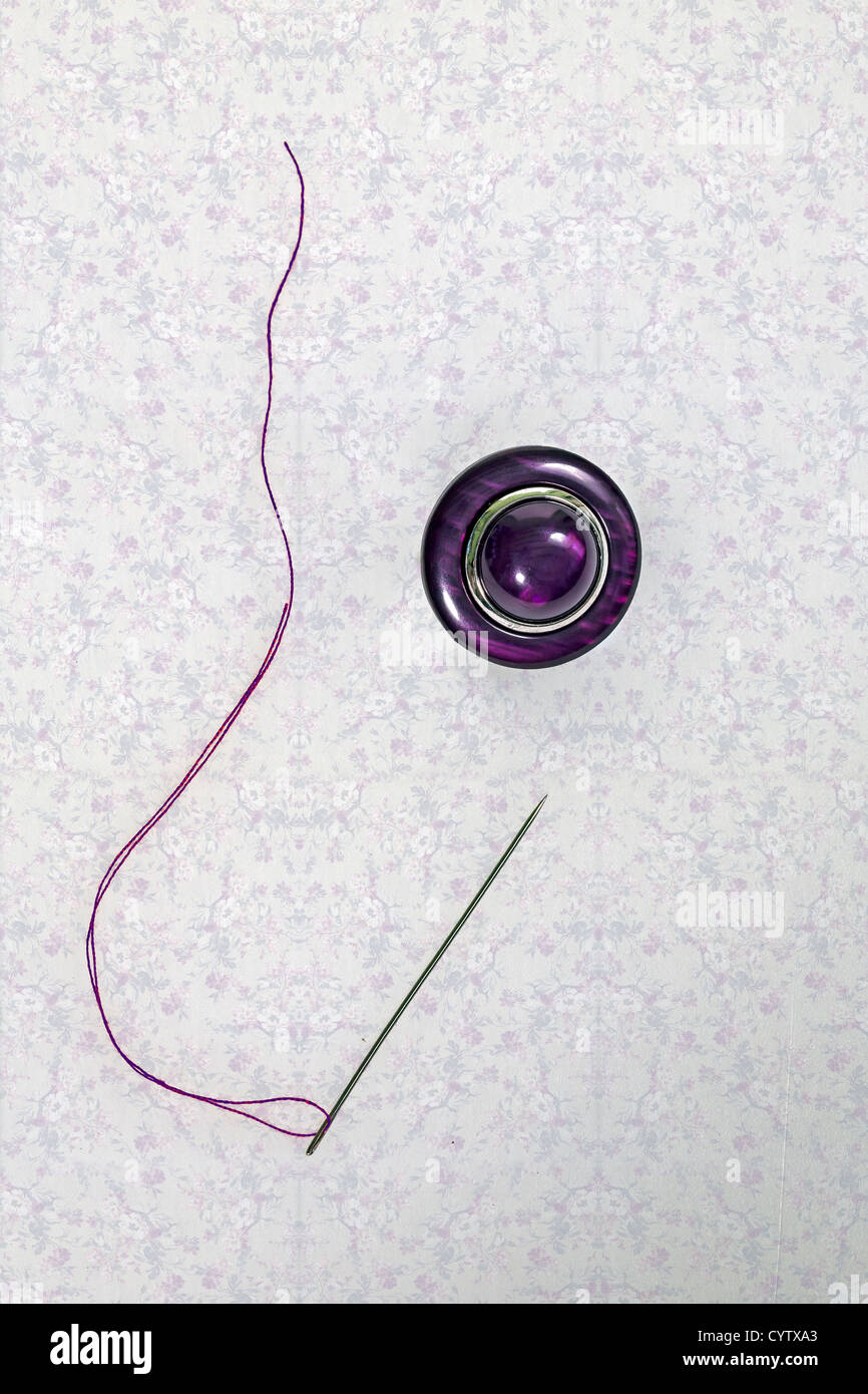 ein lila Button mit Nadel und Faden Stockfoto