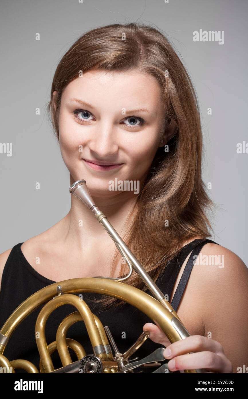 junge Musikerin mit Waldhorn Konzert im schwarzen Kleid Stockfoto