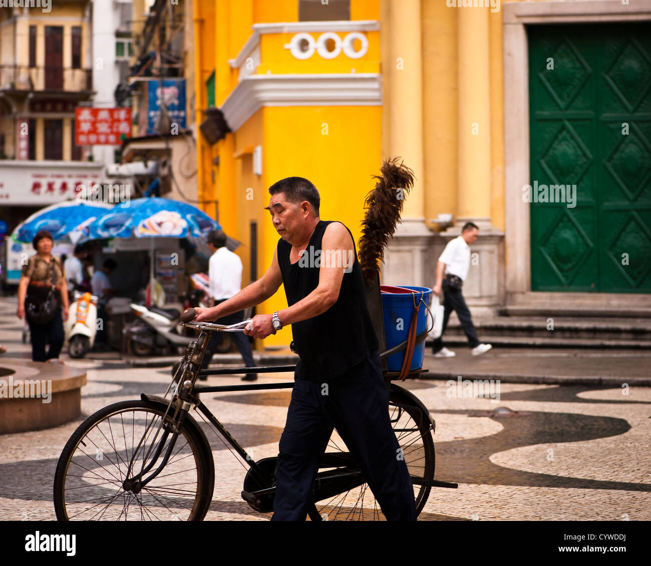 Chinesischer Mann mit buschigen Augenbrauen und Staubwedel schob sein Fahrrad vorbei an St Dominic Kirche, Macau Stockfoto