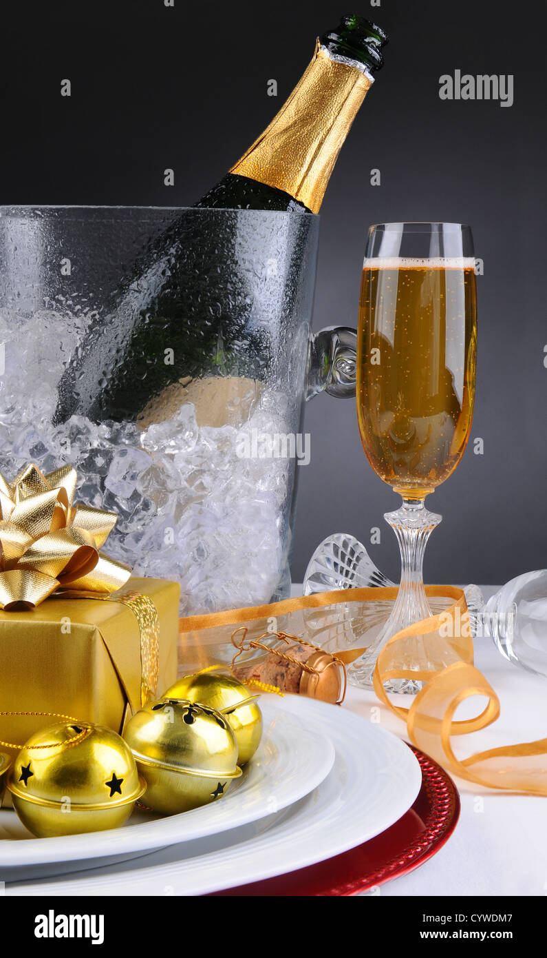Sektglas und Eiskübel auf einem dekorierten Urlaub Tisch mit Geschenken, Band und Glocken. Stockfoto