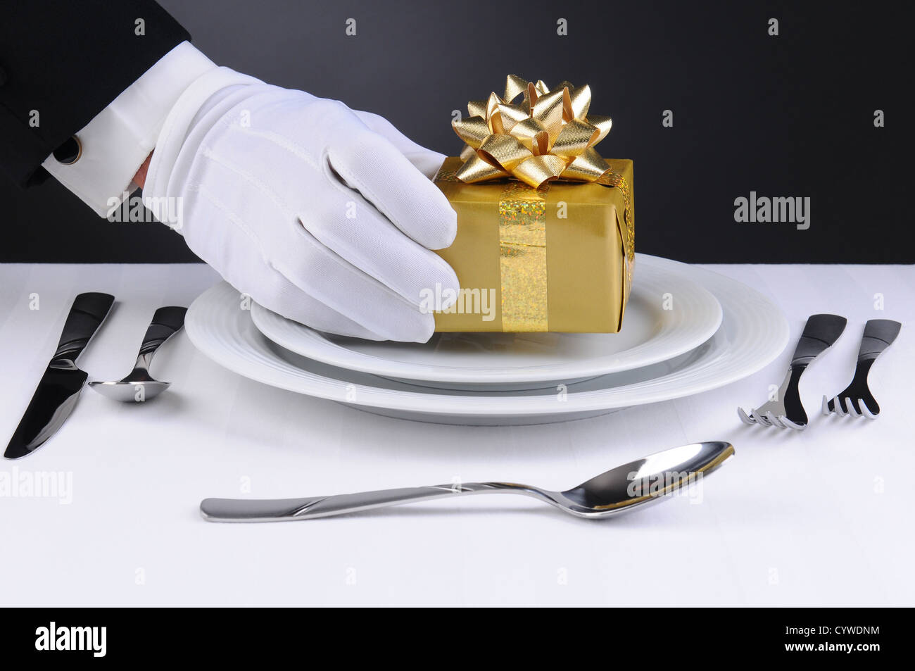 Nahaufnahme von einem Kellner behandschuhte Hand verpackte Geschenk auf dem Teller eine Formateinstellung Ort platzieren. Stockfoto