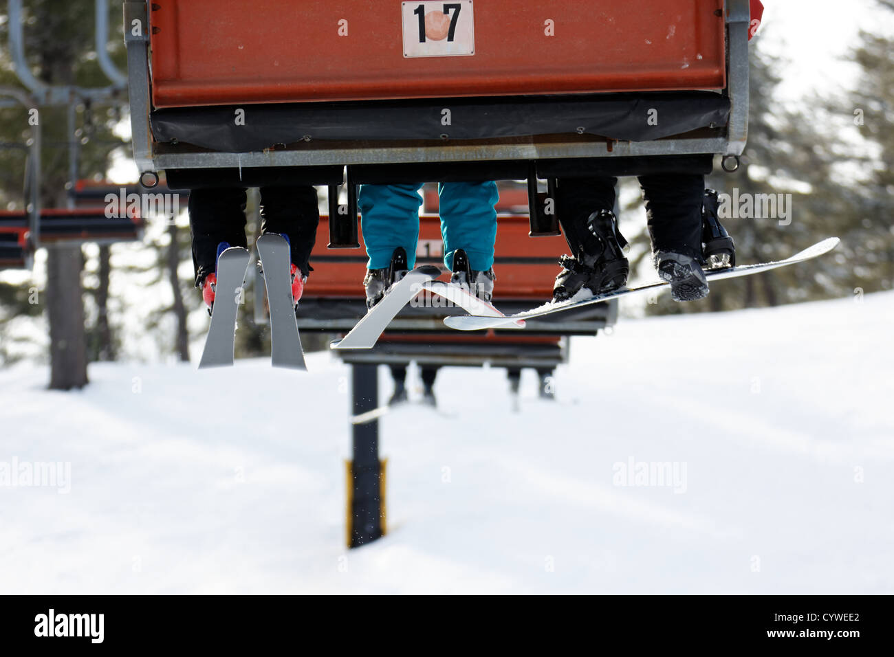 Sitzplatz in einen Skilift, von hinten gesehen, mit den Beinen seiner Fahrgäste baumeln über die Pisten. Stockfoto