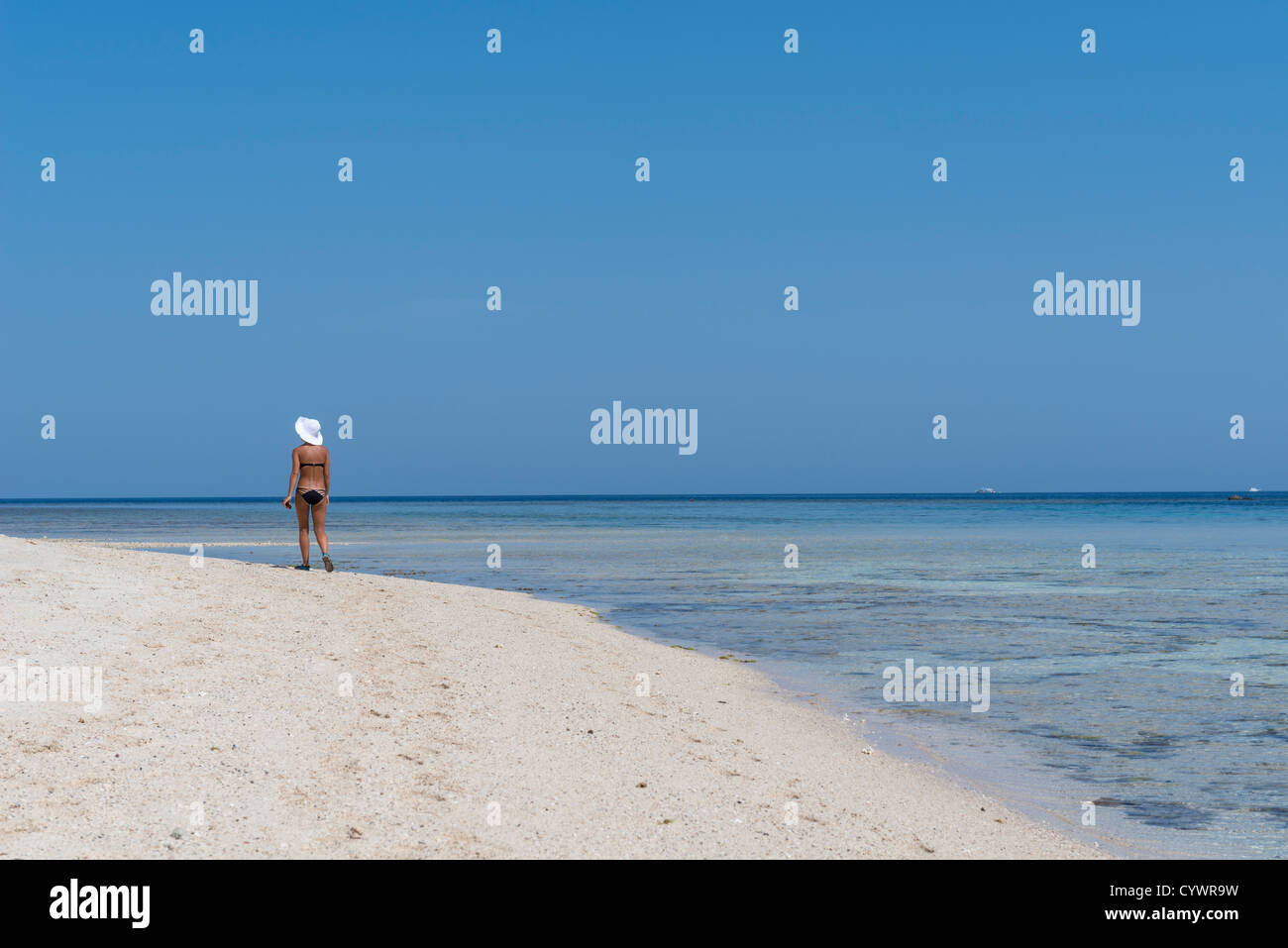 Schlanke Frau mit weißen Hut schönen Strand entlang spazieren Stockfoto