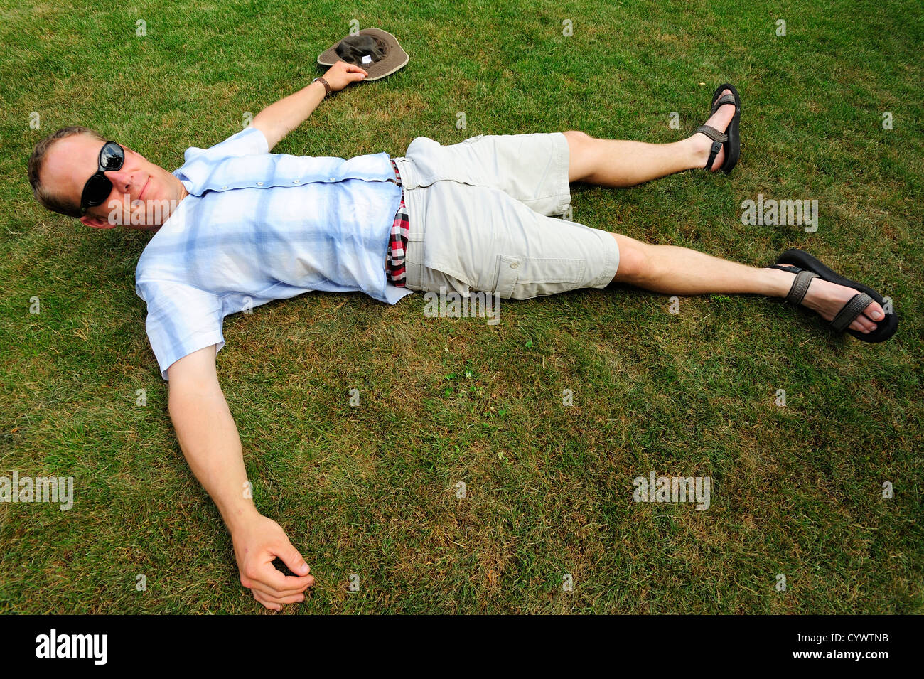 Mann in kurzen Hosen liegen Flat-out auf dem Rasen Stockfoto