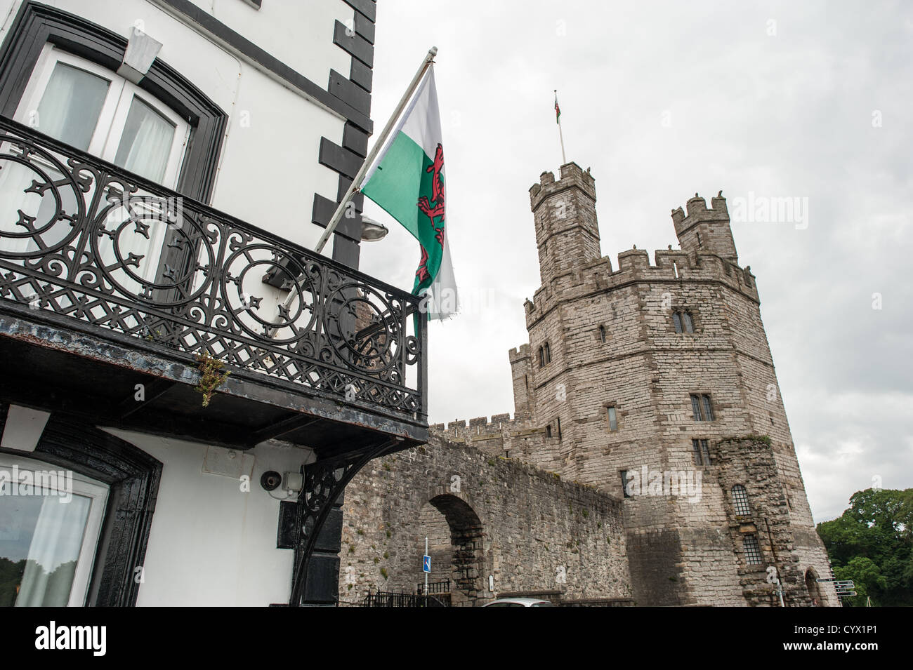 CAERNARFON, Wales – Eine walisische Flagge fliegt von der Terrasse des Anglesey Pub vor den Burgmauern von Caernarfon Castle im Nordwesten von Wales. Die mittelalterliche Festung, die von Eduard I. während seiner Eroberung von Wales im späten 13. Jahrhundert erbaut wurde, ist als UNESCO-Weltkulturerbe anerkannt. Caernarfon Castle diente als Verwaltungszentrum von Nordwales und ist eines der besten Beispiele der Militärarchitektur des späten 13. Und frühen 14. Jahrhunderts in Europa. Die Burg befindet sich in der historischen Stadt Caernarfon in Gwynedd, am Ufer der Menai-Straße. Die Festung ist weitgehend konsi Stockfoto