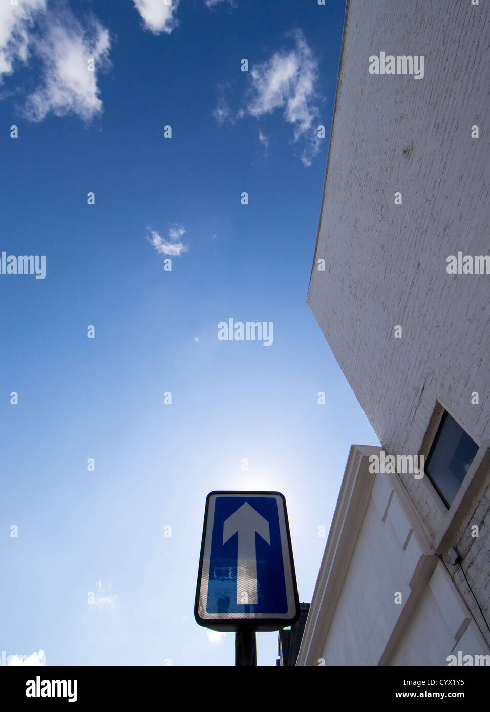 Ein weißer Pfeil auf blauem Grund zeigt auf den Himmel an einer Einbahnstraße Stockfoto