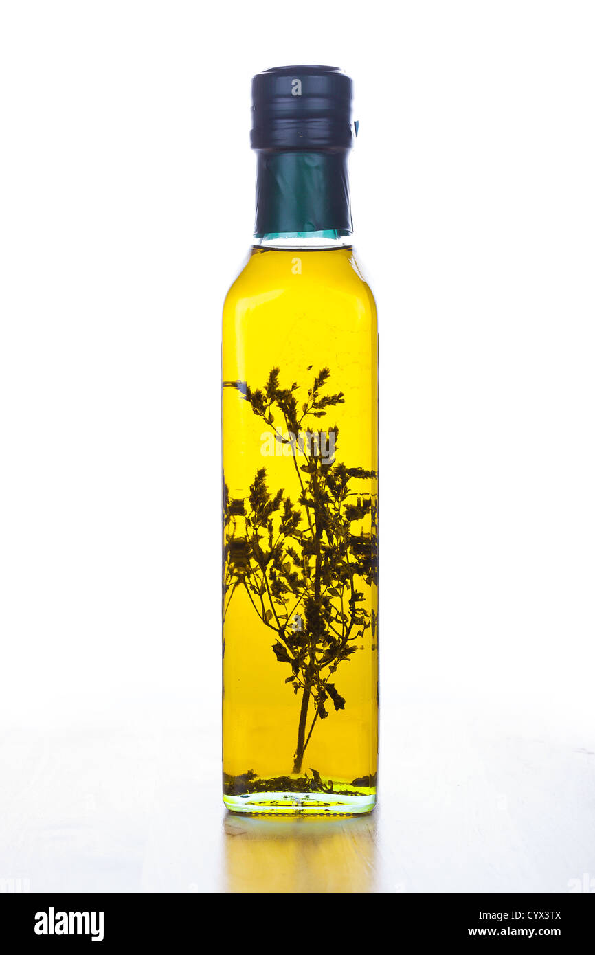 Olivenöl in Glasflasche mit Kraut in Nahaufnahme auf weiß Stockfoto