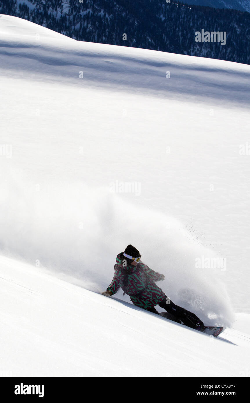 Weiblichen Snowboarder macht eine Drehung im frischen Pulverschnee Stockfoto