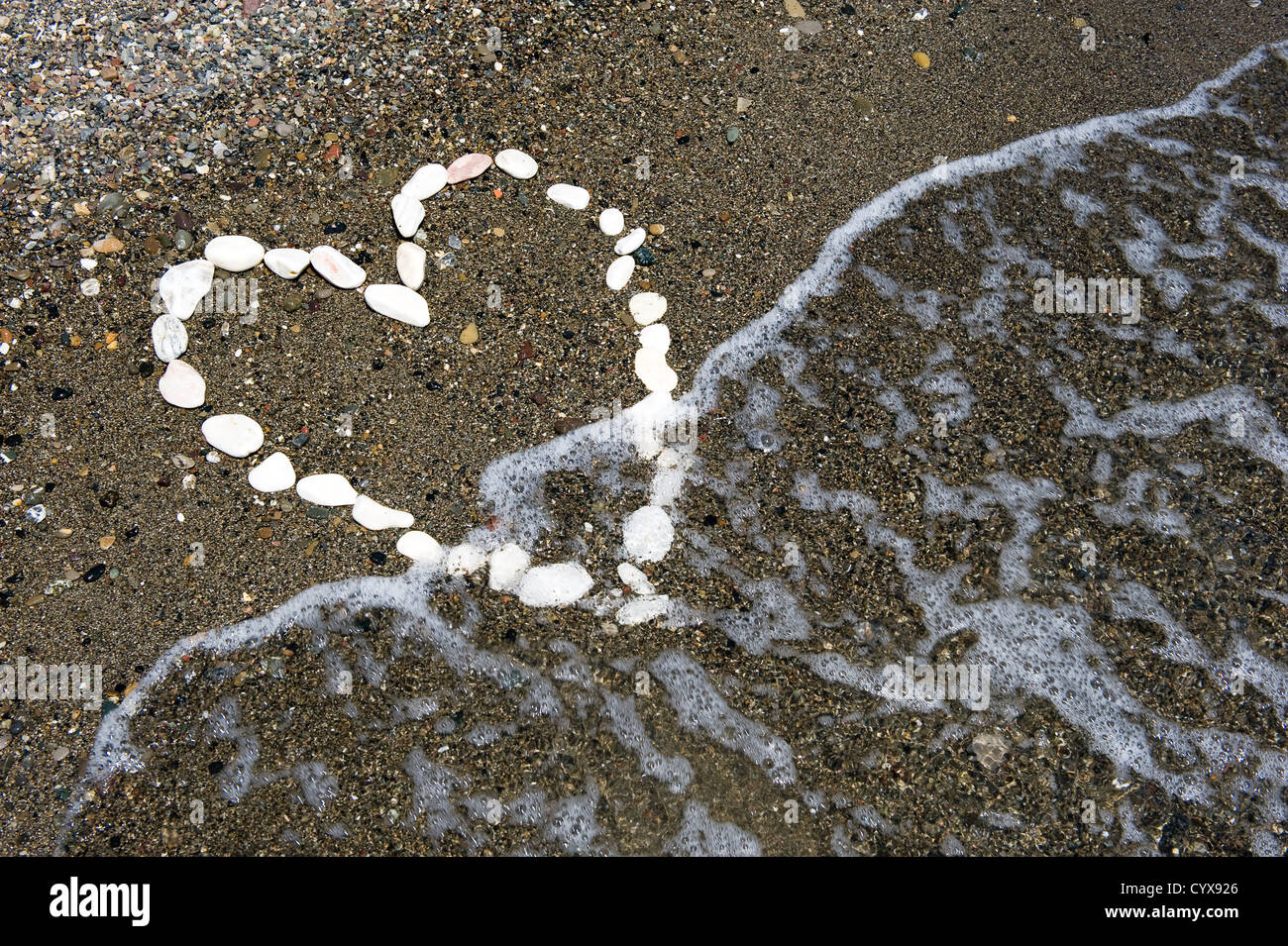 Ein Herz mit weißen Steinen am Strand gemacht Stockfoto