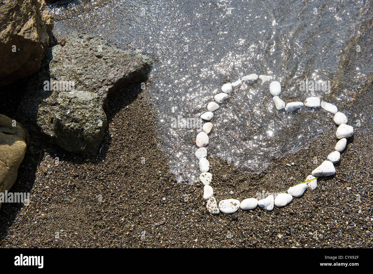 Ein Herz mit weißen Steinen am Strand gemacht Stockfoto
