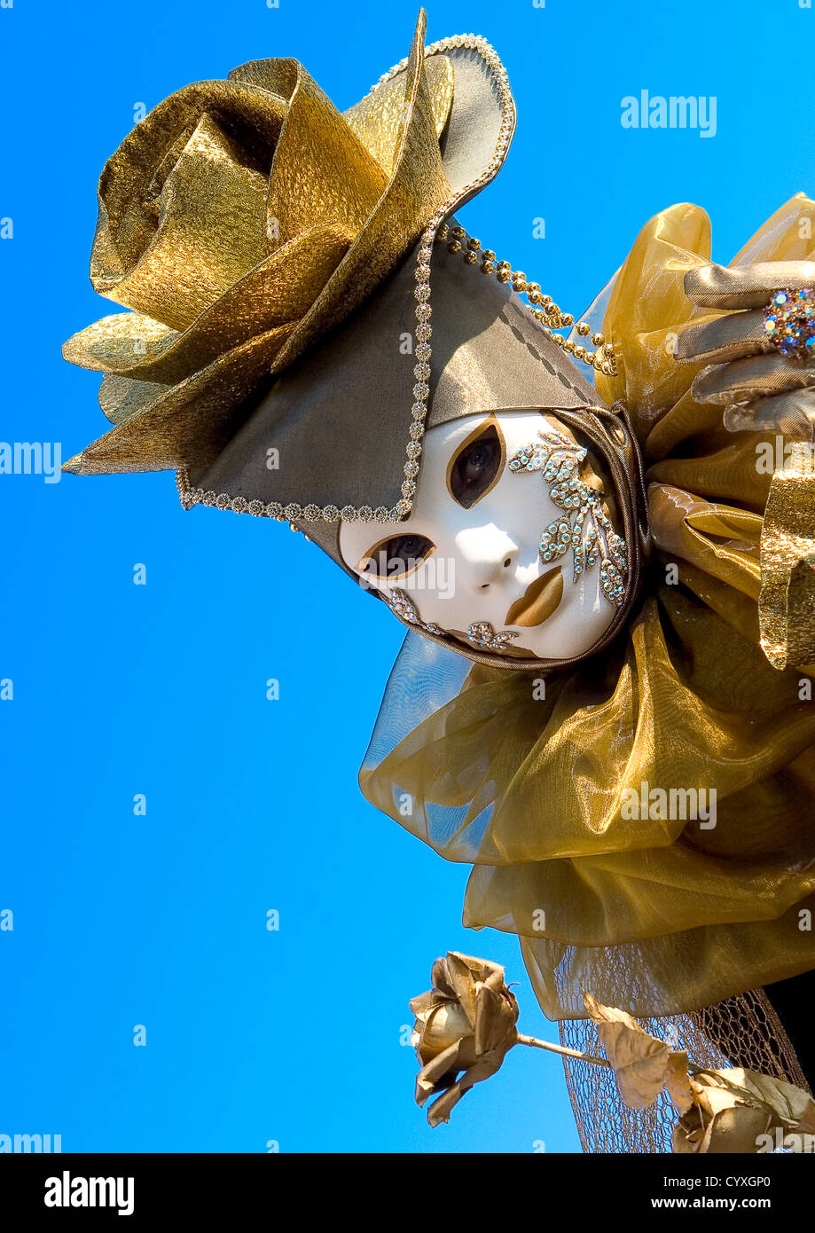 Eine Person in einem goldenen Venedig Karnevalskostüm mit einer weißen Maske Stockfoto