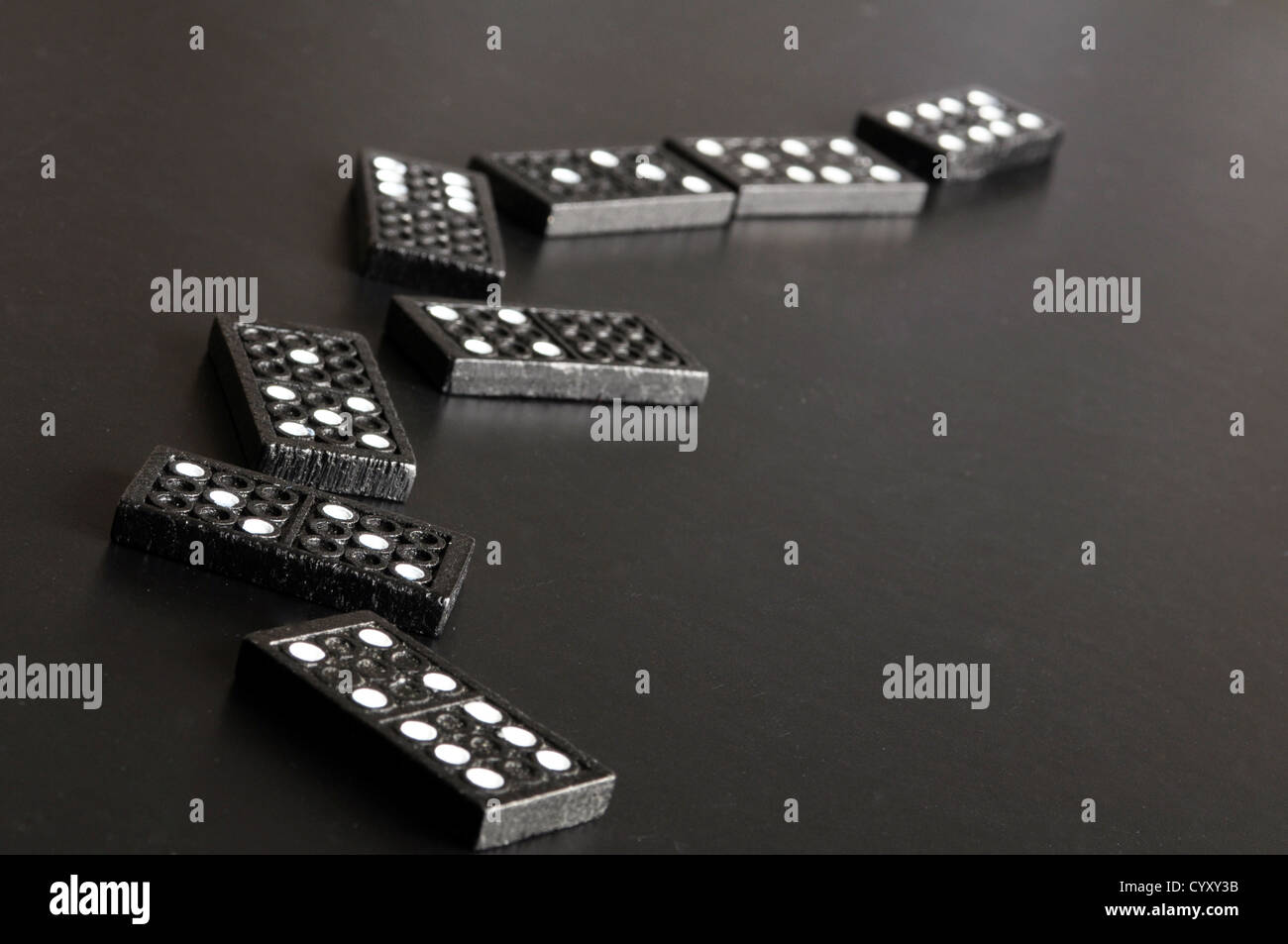 Finanzkrise-Konzept mit Domino-Spiel auf schwarzem Hintergrund Stockfoto