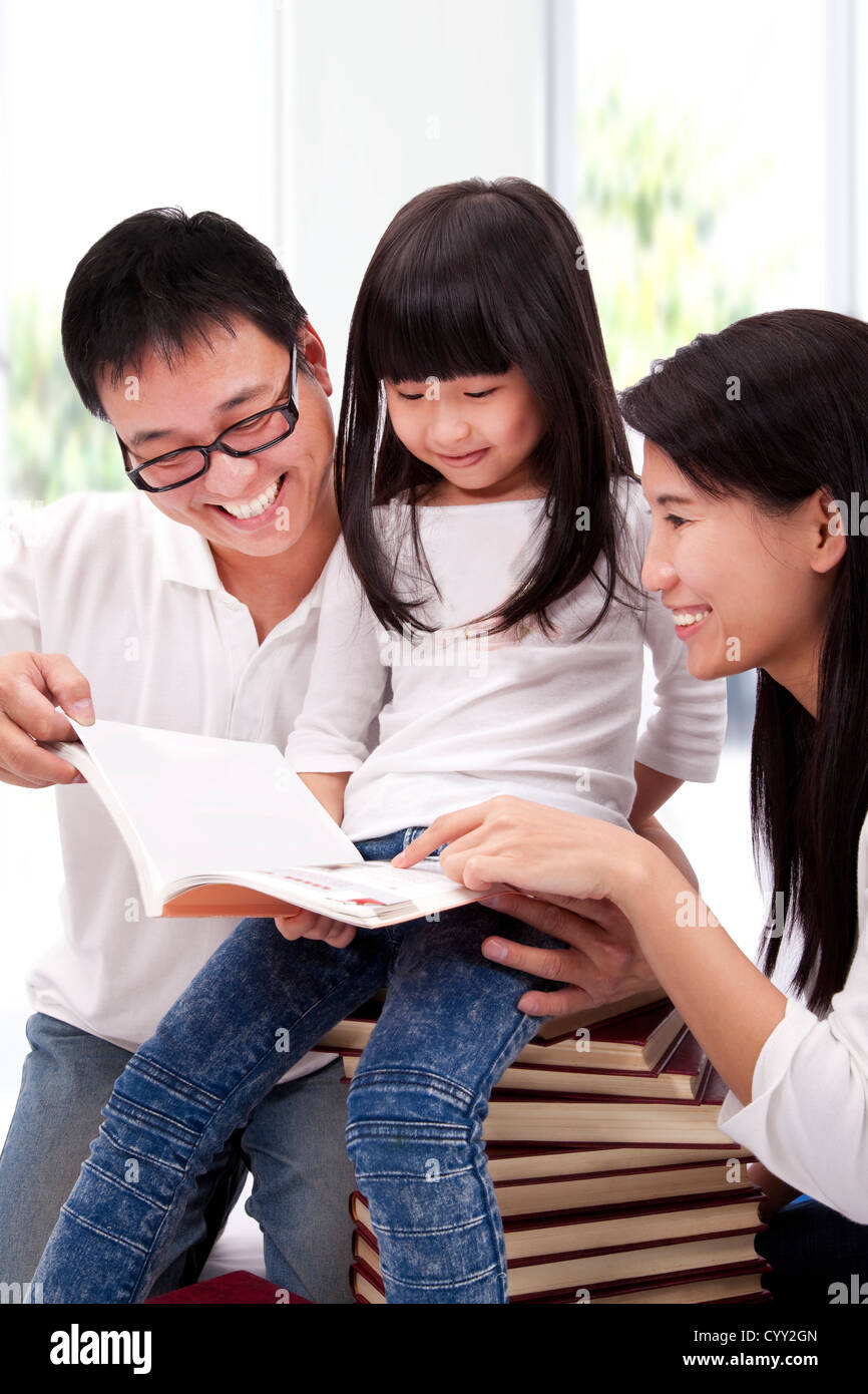 Glücklich asiatischen Familie Studing zusammen. Eltern helfen Tochter Lesebuch Stockfoto