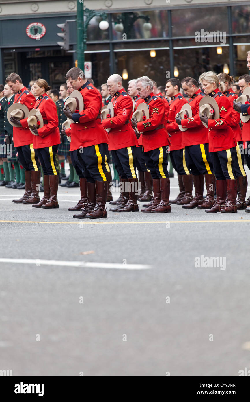 Mounties halten ihre Hüte und beugen den Kopf am Volkstrauertag am Ehrenmal in Vancouvers Siegesplatz. Stockfoto