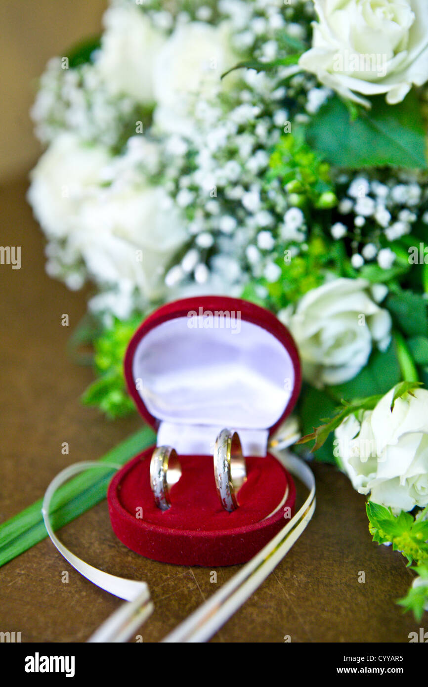 Trauringe in roten Feld in der Nähe von Strauß auf Tisch Stockfoto
