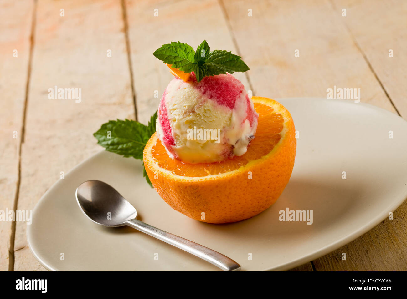 Foto von leckeren fruchtigen Eis am geschnittenen Orang mit frischer Minze Blätter Stockfoto