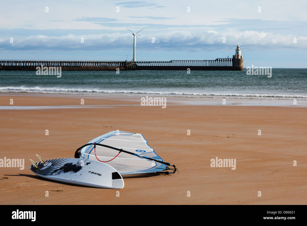 Windsurfer am Strand von Blyth, mit dem Hafen Arme und Windkraftanlage in der Ferne, Northumberland, UK Stockfoto